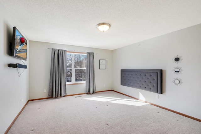 carpeted empty room with a textured ceiling, visible vents, and baseboards