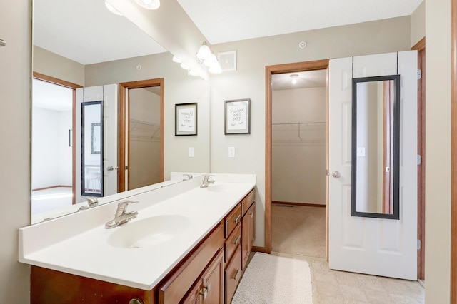 bathroom with double vanity, a spacious closet, and a sink