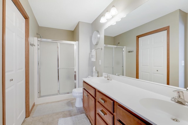 full bathroom with a sink, a shower stall, and double vanity