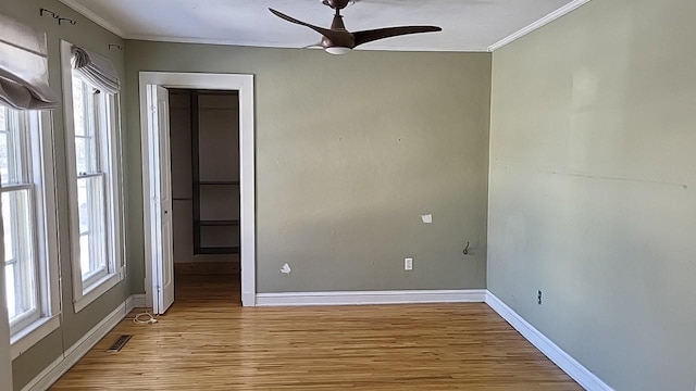 unfurnished room with plenty of natural light, light wood-style floors, baseboards, and ornamental molding