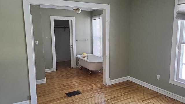 bathroom featuring a soaking tub, baseboards, and wood finished floors