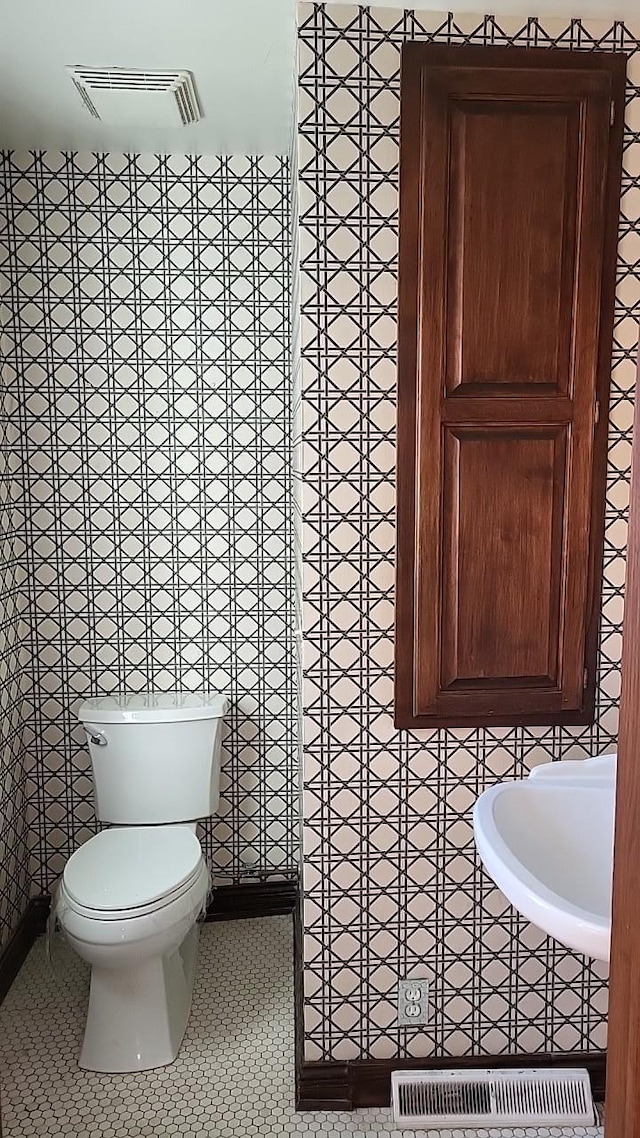 bathroom with tile patterned flooring, visible vents, and toilet