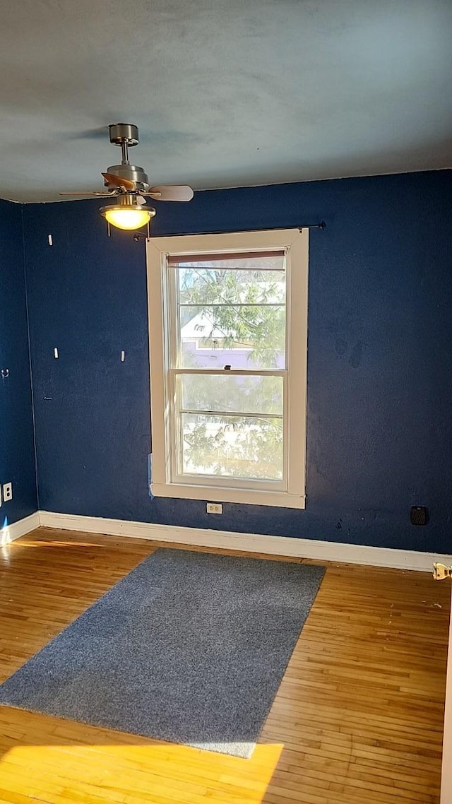 unfurnished room with ceiling fan, baseboards, and wood finished floors