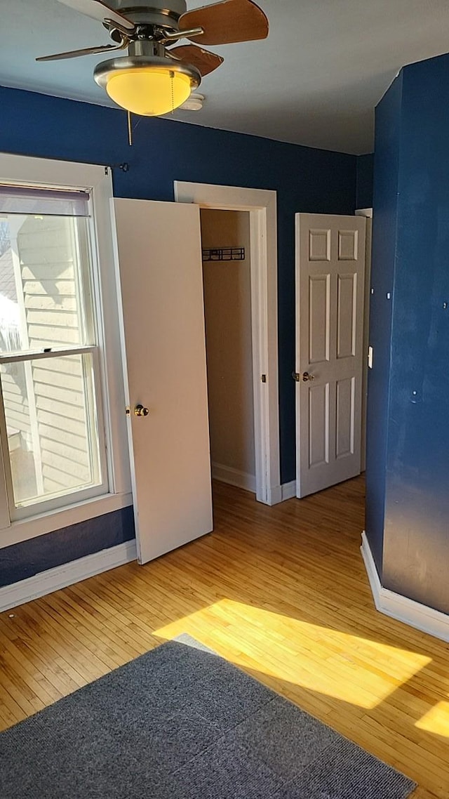 unfurnished bedroom featuring light wood finished floors, a ceiling fan, and baseboards