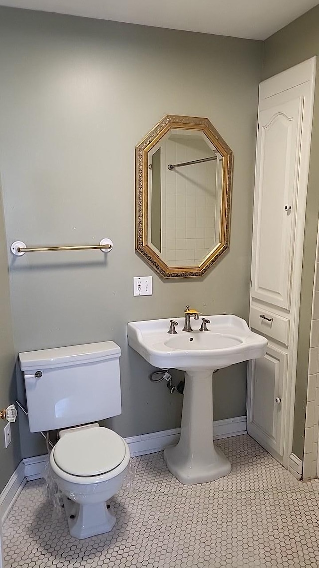 bathroom featuring toilet, tile patterned flooring, baseboards, and a sink