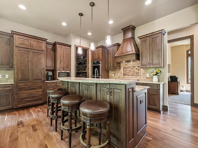 4350 Golfview Dr, Jordan, MN 55352 - kitchen featuring premium range hood, appliances with stainless steel finishes, a kitchen island with sink, wood finished floors, and recessed lighting