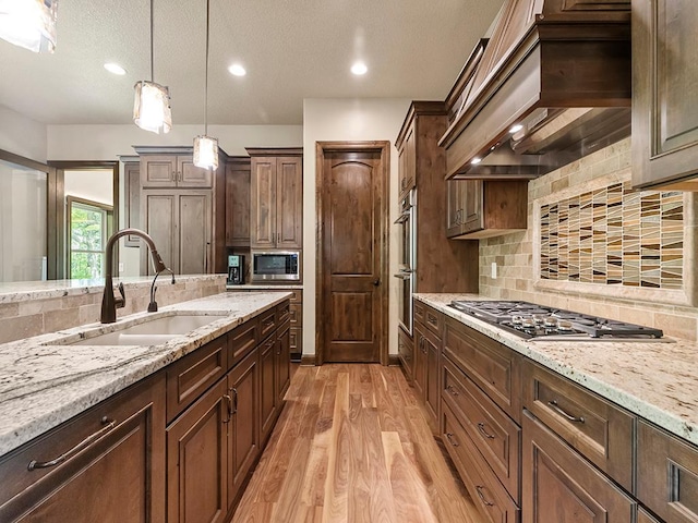 4350 Golfview Dr, Jordan, MN 55352 - kitchen with stainless steel appliances, a sink, light wood-type flooring, pendant lighting, and light stone counters