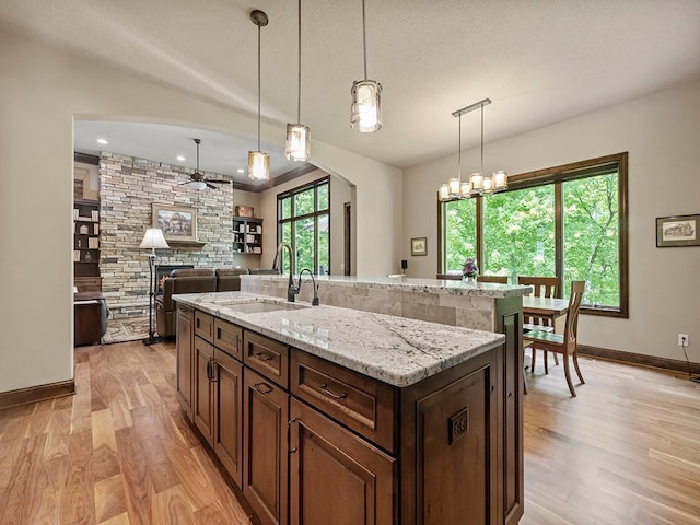 4350 Golfview Dr, Jordan, MN 55352 - kitchen with a sink, light wood-type flooring, a fireplace, baseboards, and light stone countertops