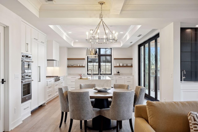 dining room featuring light wood finished floors, visible vents, a tray ceiling, crown molding, and a chandelier