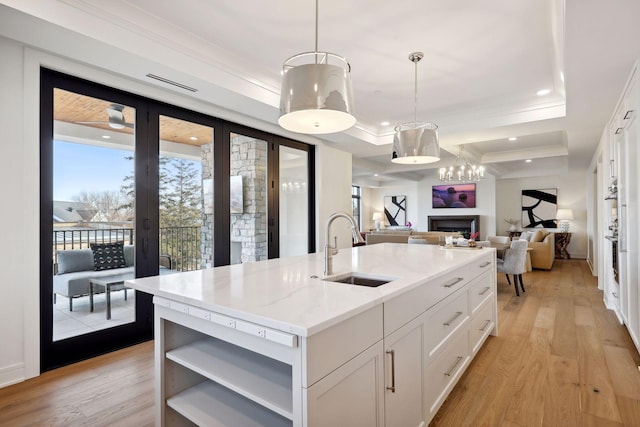 kitchen featuring a fireplace, open shelves, white cabinetry, a sink, and light wood-type flooring