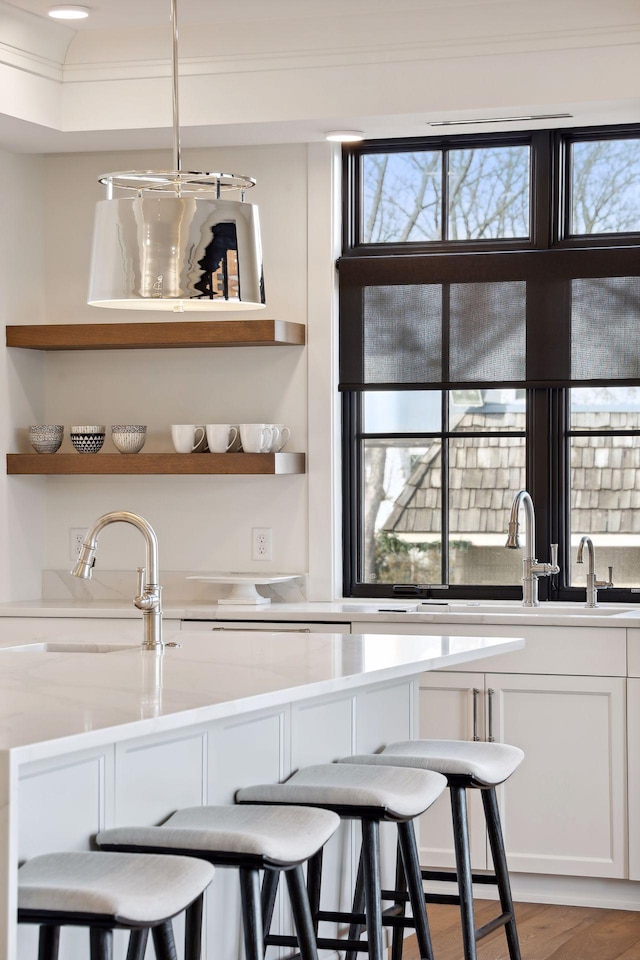 bar featuring a sink, light wood-style flooring, crown molding, and a wealth of natural light