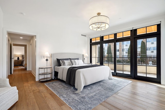 bedroom featuring access to exterior, visible vents, baseboards, and hardwood / wood-style flooring