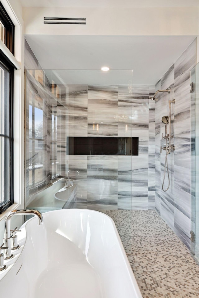 full bath featuring a stall shower, a freestanding tub, and visible vents