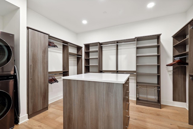 spacious closet with light wood finished floors and stacked washer / drying machine