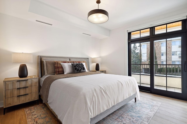 bedroom with access to exterior, light wood-style flooring, and visible vents