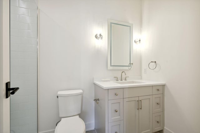 full bath featuring toilet, a shower, vanity, and baseboards