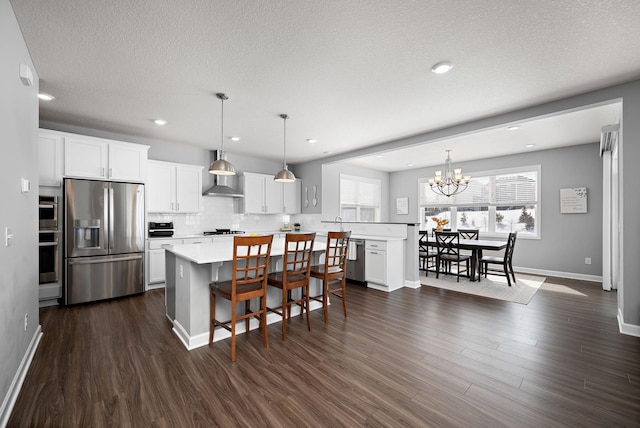 kitchen featuring a breakfast bar, dark wood finished floors, light countertops, appliances with stainless steel finishes, and wall chimney range hood