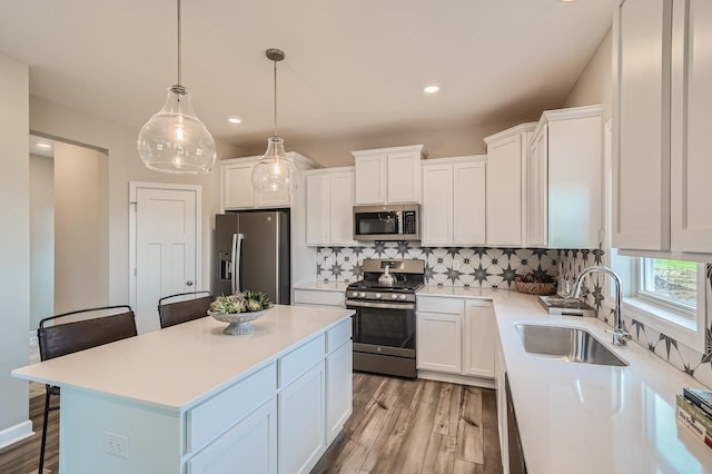 kitchen with tasteful backsplash, appliances with stainless steel finishes, light countertops, white cabinetry, and a sink