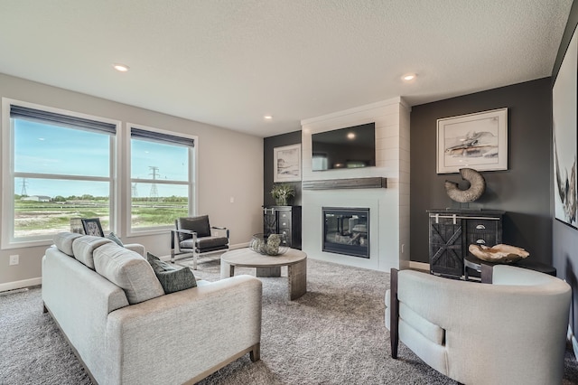 carpeted living room with a large fireplace, baseboards, a textured ceiling, and recessed lighting