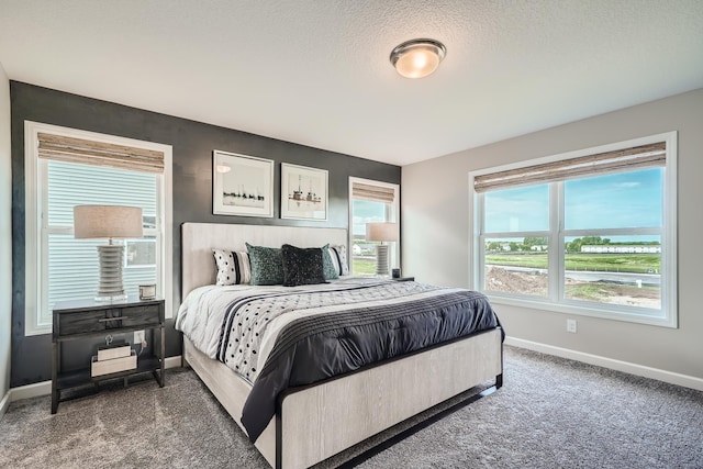 bedroom featuring a textured ceiling, dark carpet, and baseboards