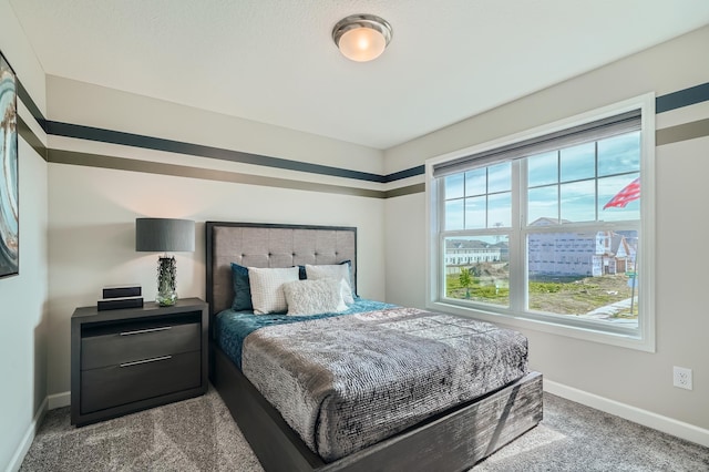 bedroom with baseboards and dark carpet