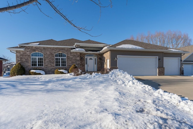 view of front of house with an attached garage, driveway, and brick siding