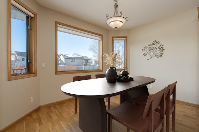 dining room featuring light wood finished floors and baseboards