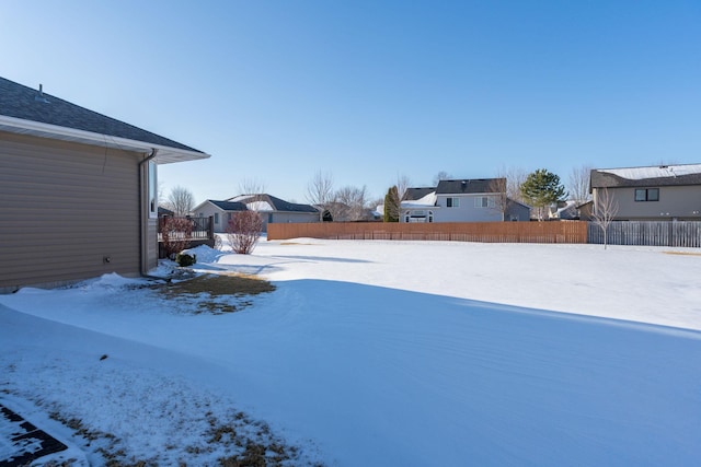 yard layered in snow featuring a residential view and fence