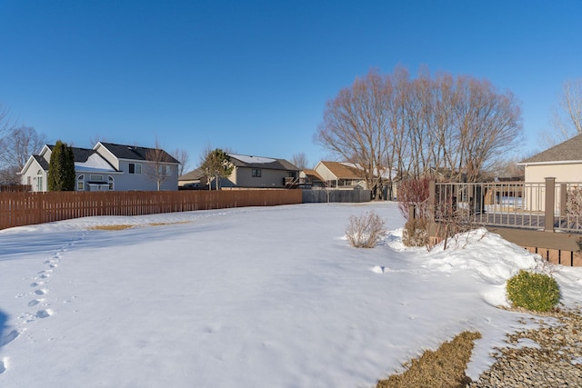 snowy yard with a residential view and fence