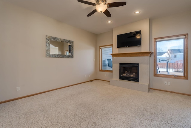 unfurnished living room with baseboards, a ceiling fan, a glass covered fireplace, carpet flooring, and recessed lighting