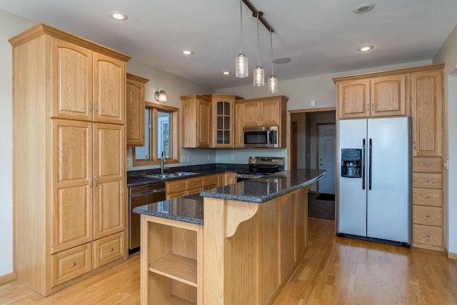 kitchen featuring stainless steel appliances, a sink, light wood-type flooring, a center island, and glass insert cabinets