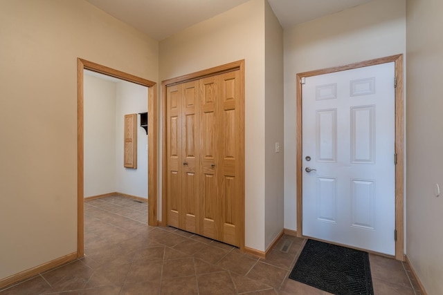 foyer entrance with dark tile patterned floors and baseboards