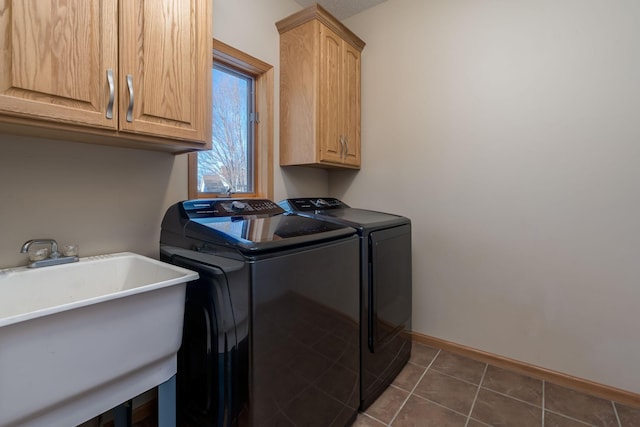 laundry room with cabinet space, washing machine and dryer, a sink, dark tile patterned floors, and baseboards