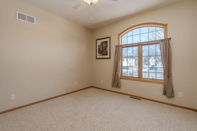 empty room featuring carpet, visible vents, ceiling fan, and baseboards