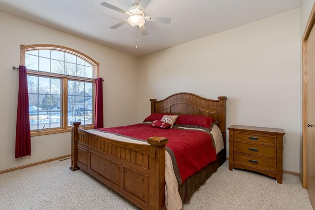 bedroom featuring a ceiling fan, baseboards, a textured ceiling, and light colored carpet