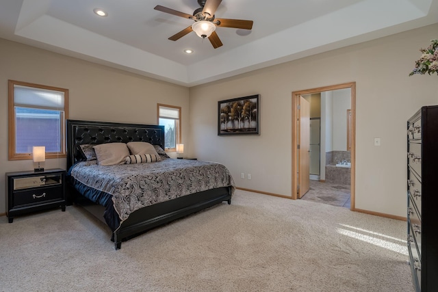 carpeted bedroom featuring ensuite bath, baseboards, a tray ceiling, and recessed lighting