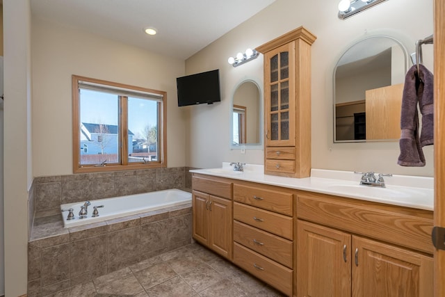 full bathroom featuring double vanity, a garden tub, tile patterned flooring, and a sink