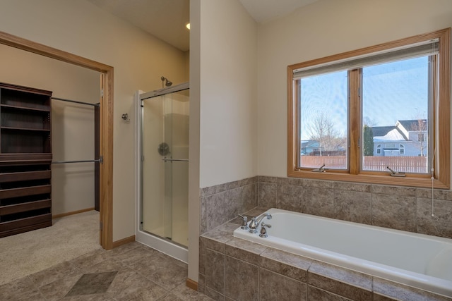 bathroom featuring a garden tub, a shower stall, and baseboards