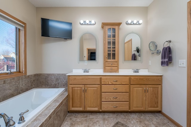 full bathroom with double vanity, a sink, and a bath