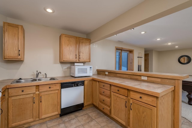 kitchen featuring white microwave, a peninsula, a sink, tile counters, and dishwasher