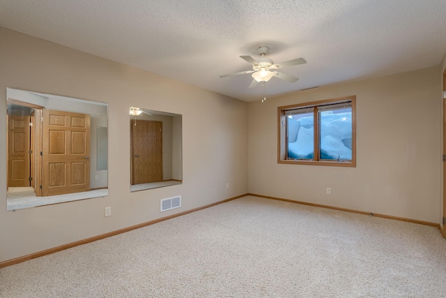 carpeted spare room with ceiling fan, a textured ceiling, visible vents, and baseboards