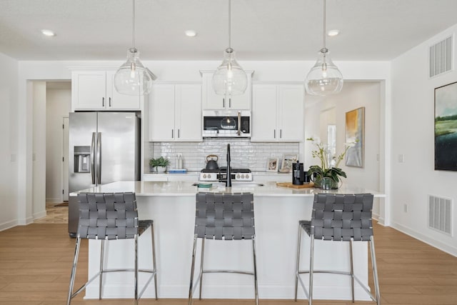 kitchen featuring appliances with stainless steel finishes, visible vents, light wood-style floors, and tasteful backsplash