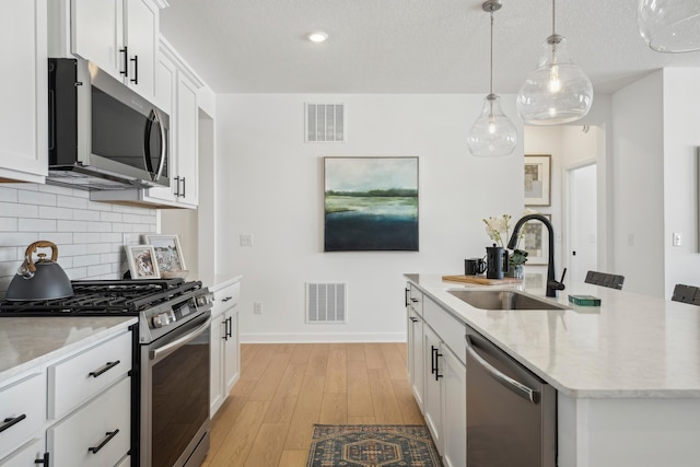 kitchen featuring stainless steel appliances, a sink, visible vents, and decorative backsplash