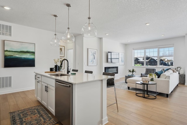 kitchen featuring a sink, visible vents, open floor plan, and stainless steel dishwasher