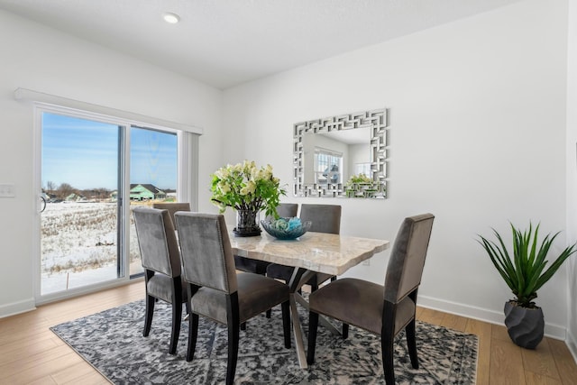 dining space featuring light wood finished floors and baseboards