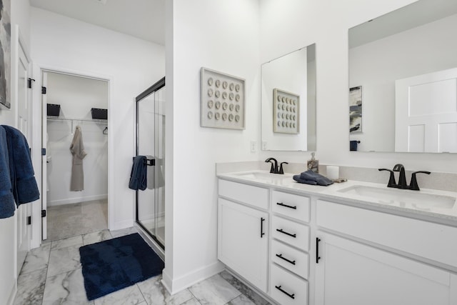 bathroom featuring marble finish floor, a shower stall, a walk in closet, and a sink