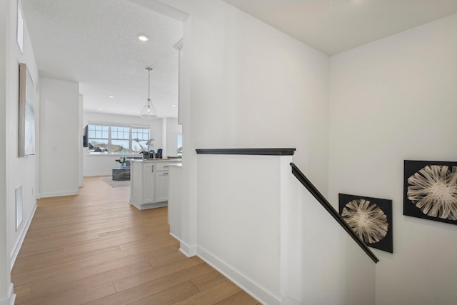 corridor with visible vents, baseboards, light wood-style flooring, an upstairs landing, and recessed lighting