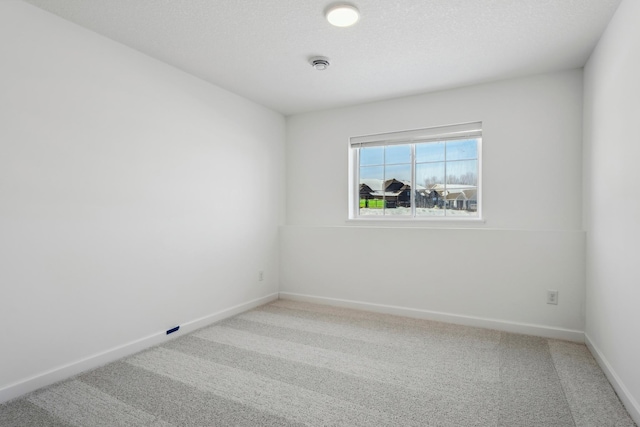 unfurnished room featuring light carpet, a textured ceiling, and baseboards