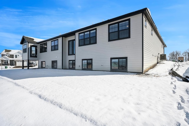 snow covered back of property featuring central air condition unit