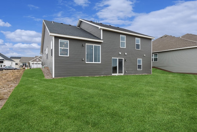 back of house featuring a shingled roof and a lawn